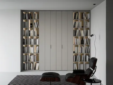 Libreria a giorno lineare e geometrica, in laccato opaco, arricchita dalla schiena in laccato metallico Oxid e impreziosita dall’illuminazione a led passaggio porta di Caccaro